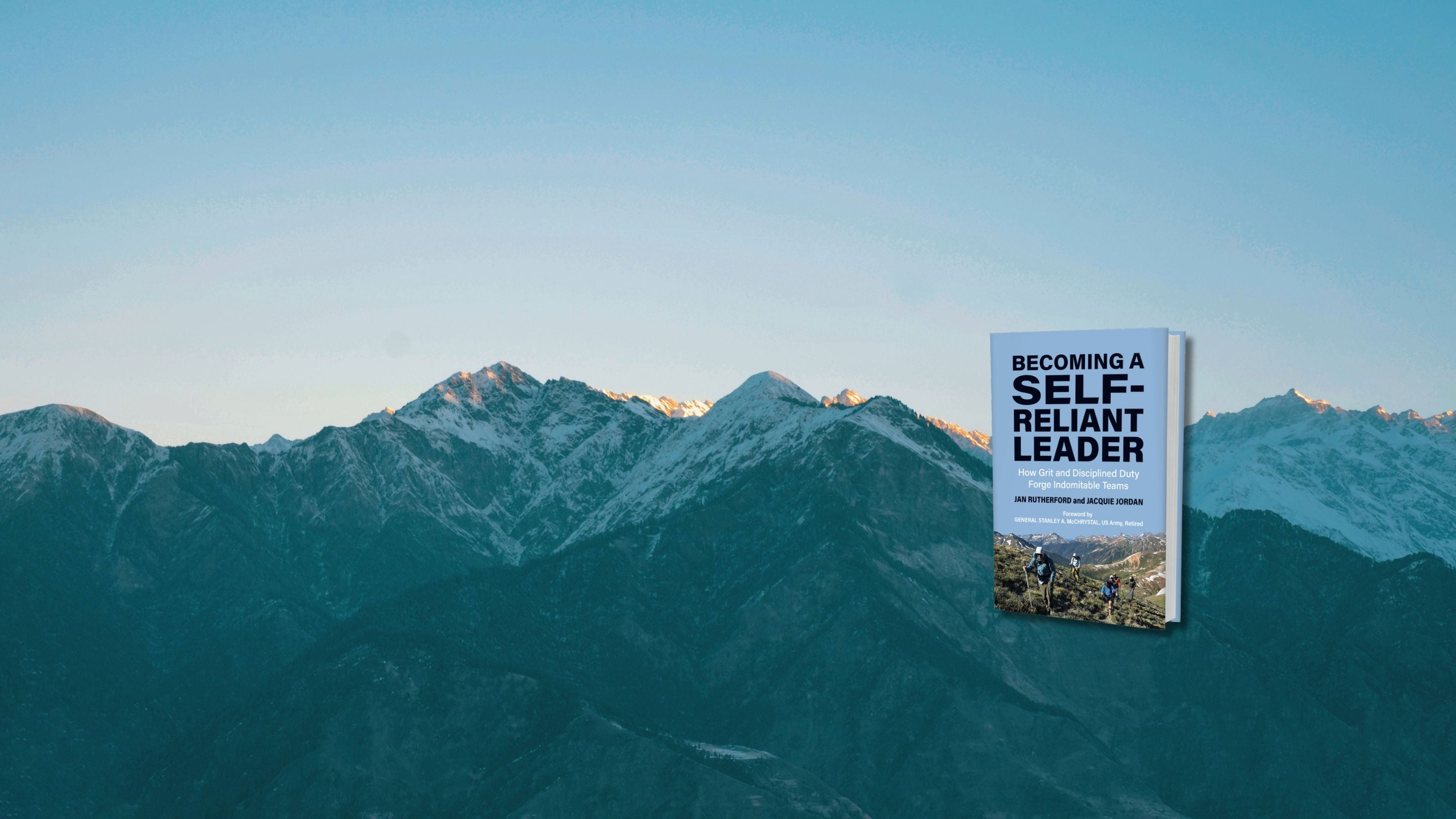 mountains at sunrise with book Becoming a Self-Reliant Leader